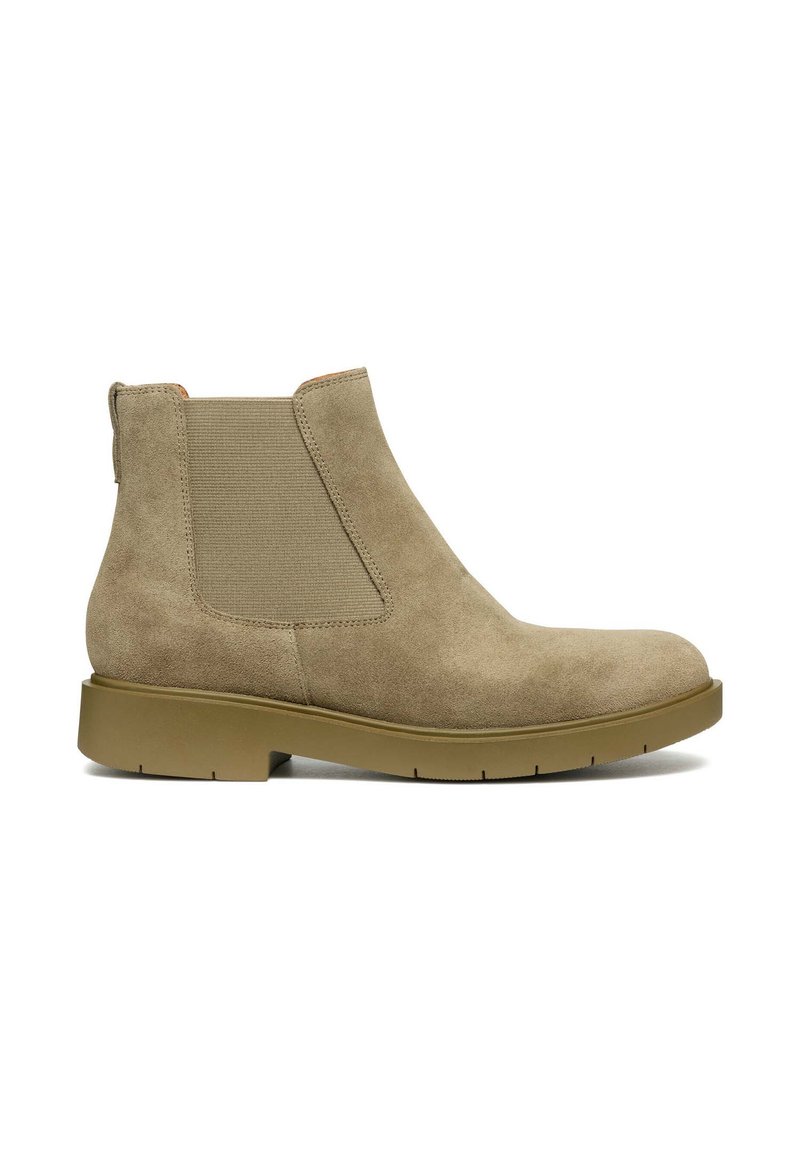 Stivale alla caviglia in suede beige con pannelli laterali elasticizzati, punta rotonda e una robusta suola in gomma. Superficie texturizzata con dettagli di cucitura minimi.