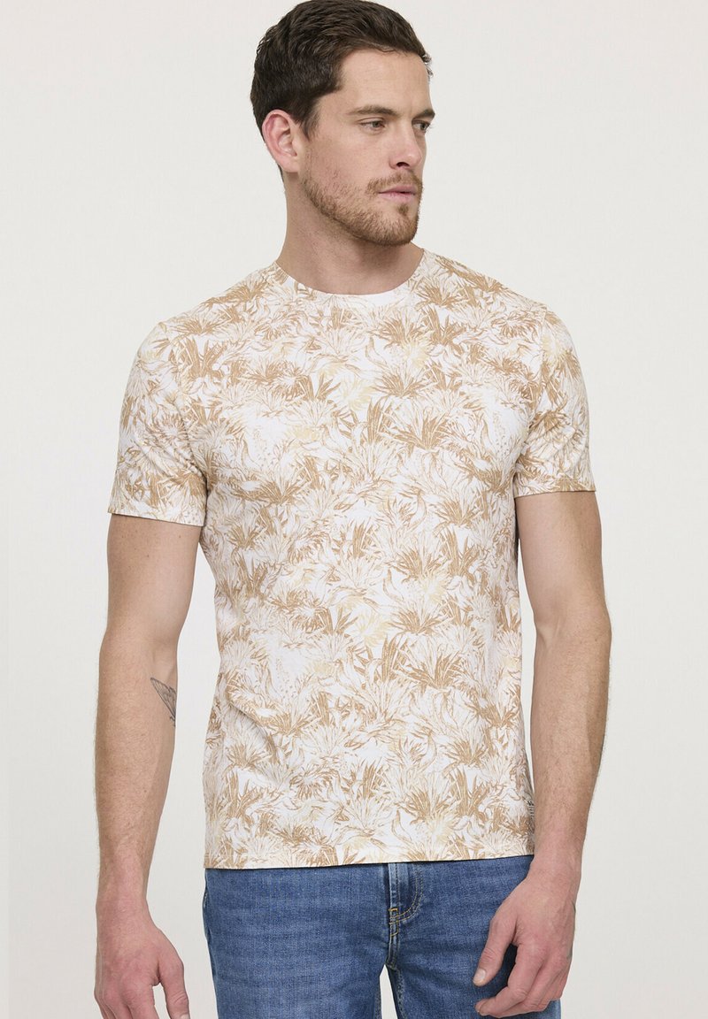 T-shirt à manches courtes en tissu léger. Présente un motif de feuilles beige et blanc. Design ajusté avec un col rond.