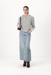 Gestreifter Hoodie in Schwarz und Weiß, hellblauer Jeans-Maxikleid, braune Knöchelstiefel, kleine schwarze Handtasche, simples Design, lässiger Look.