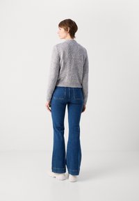 Gray textured sweater, cropped design, paired with blue flared jeans. The outfit features a simple, casual style with minimal accents.