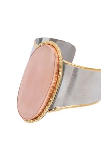 Silverfärgad manschettarmband med en polerad rosa stencenter, guldaccent runt stenen, slät textur och elliptisk form.