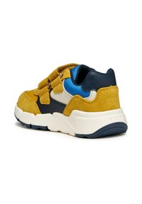 Sneaker met gele suède, marineblauwe leren accenten en een blauwe stoffen voering. Beschikt over klittenbandsluitingen en een dikke witte zool met blauwe details.
