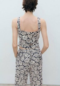 Top corto floreale blu navy con spalline larghe e schiena quadrata, abbinato a pantaloni a vita alta che presentano lo stesso motivo floreale.