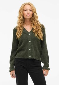 Donkergroene cardigan met een V-hals, textuurstof en zes witte knoopsluitingen; lange mouwen met manchet details.