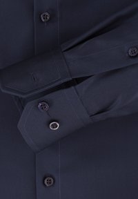 Donker marineblauw overhemd met een fijne textuur, punten manchet en twee donkere knopen op elke manchet. Netjes stiksels accentueren het ontwerp.