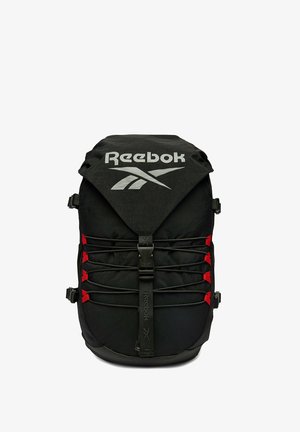 Zaino nero Reebok con grande logo, corde elastiche frontali fissate da linguette rosse e chiusura a fibbia centrale.