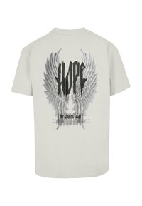 Lys grå bomulds t-shirt med et stort sort-hvidt grafisk motiv af englevinger og ordet "HOPE" ovenfor, samt tekst nedenfor.