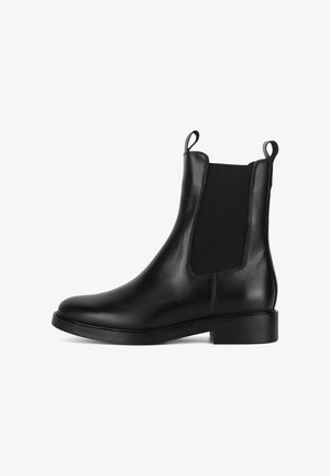 Bota Chelsea de piel negra con paneles laterales elásticos, tiradores, punta redondeada y tacón plano. Textura suave con diseño minimalista.