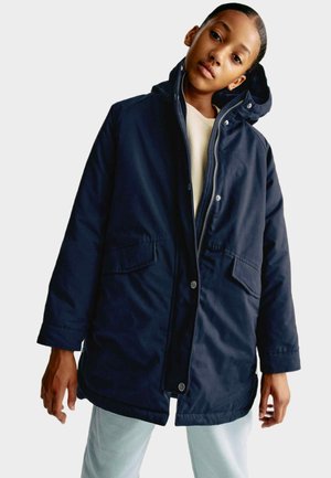 Marinblå isolerad parka med dragkedja framtill, tryckknappar, två framfickor och huva. Fin struktur med en avslappnad passform.