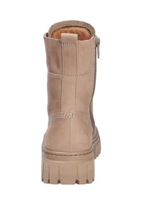 Bottine en suède beige avec un cuir texturé, fermeture éclair sur le côté et semelle en caoutchouc épaisse présentant des rainures horizontales pour une meilleure traction.