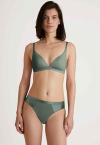 Groene bralette met een driehoekig ontwerp en dunne bandjes, gecombineerd met een bijpassende bikini onderkant, beide gemaakt van gladde stof.