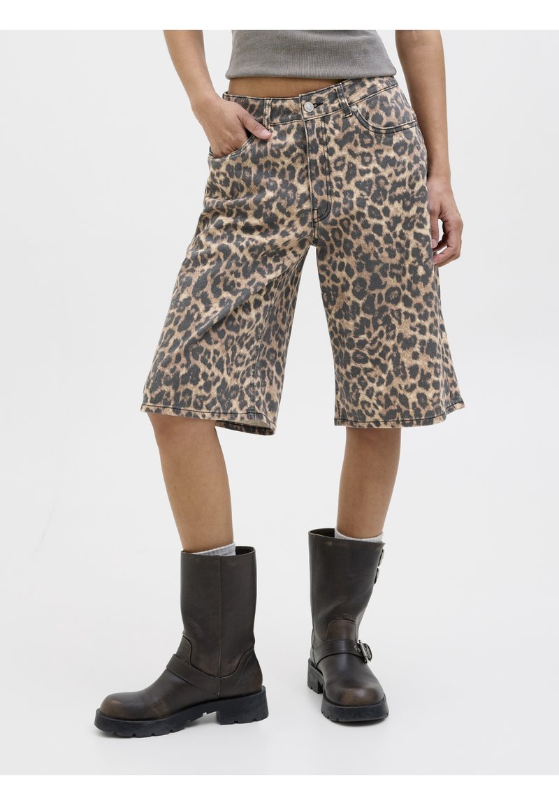 Shorts en denim imprimé léopard avec une coupe décontractée, dotés de poches avant et d'ourlets roulés, associés à des bottes noires mi-mollet.