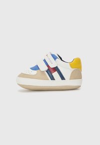 Sneaker con punta in suede beige, accenti blu e rossi, strisce bianche e blu navy, e tacco giallo. Presenta due cinghie in Velcro per la chiusura.