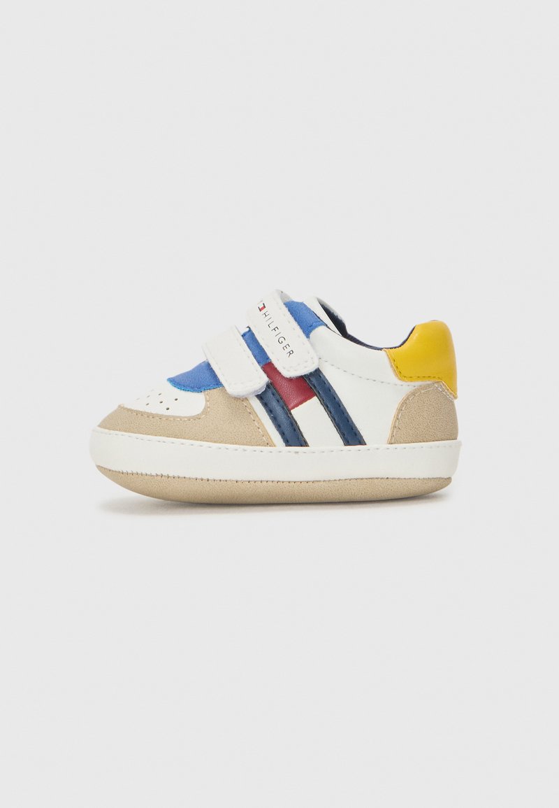 Sneaker con punta in suede beige, accenti blu e rossi, strisce bianche e blu navy, e tacco giallo. Presenta due cinghie in Velcro per la chiusura.