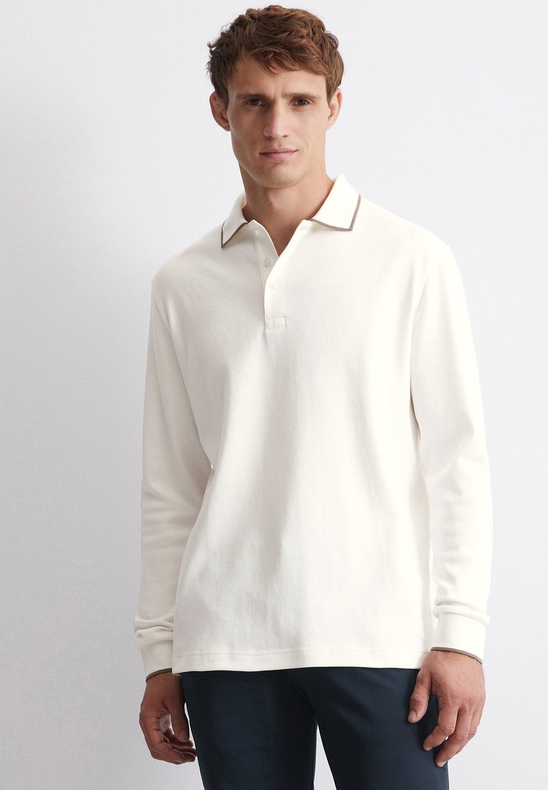 Langärmliges Poloshirt aus cremefarbener Baumwolle mit kontrastierendem braunem Kragenbesatz, ausgestattet mit einer Knopfleiste und lockerem Schnitt. Glatte Textur, kein Muster.