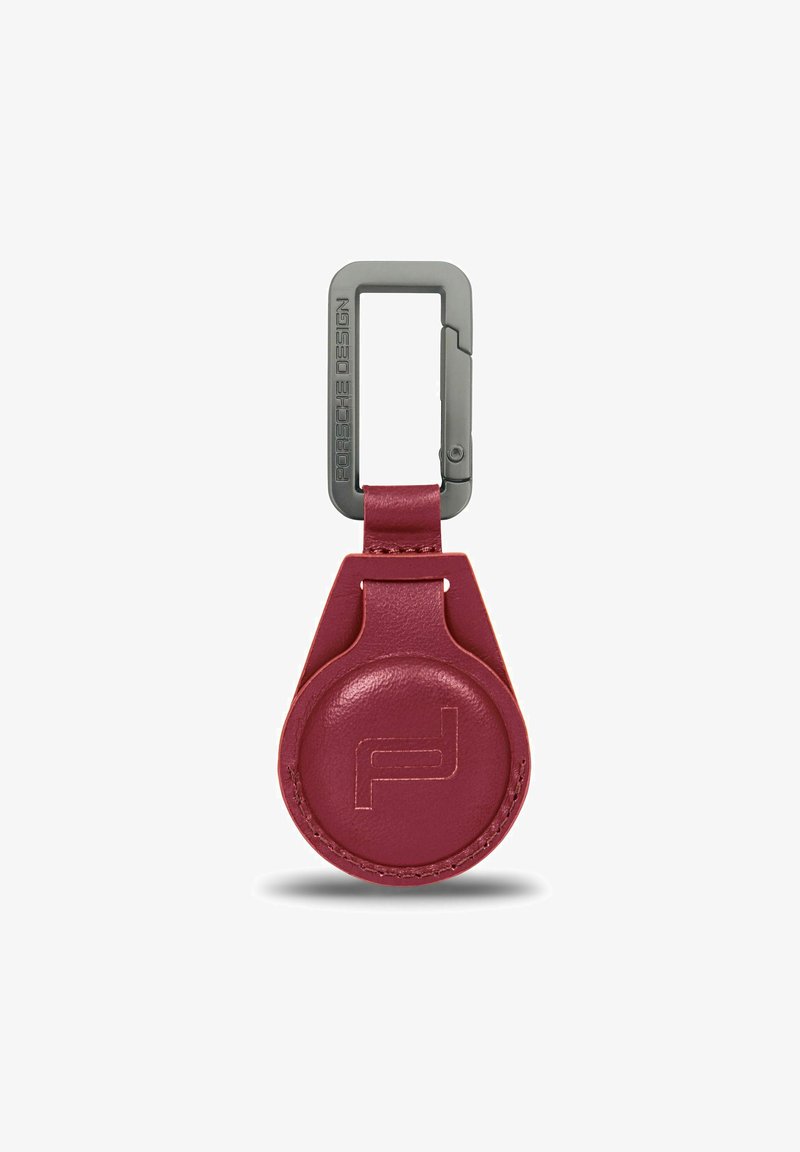 Porsche Design sleutelhanger van bordeauxleder met een ronde body, een debossed logo en een matte grijze metalen clip in rechthoekige vorm.
