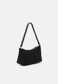 Sac d'épaule en nylon noir avec une texture lisse, une forme incurvée et une bandoulière unique et réglable. Comprend une fermeture éclair argentée sur le dessus.