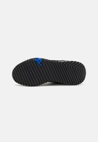 Svart sneakersåle med en teksturert, ribbet overflate og et blått logoakcent. Designet fremhever bedre grep og stabilitet.