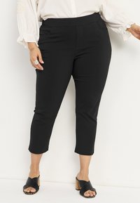 Zwarte cropped broek met een gladde textuur, een middelhoog taille en twee zijzakken. Draag het met zwarte hakken met kruisbanden en een kurken hak.
