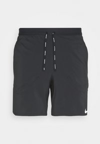 Pantalones cortos deportivos negros de Nike con cintura ajustable con cordón, bolsillos laterales y un pequeño logotipo blanco en la parte inferior de la pierna derecha. Textura suave.