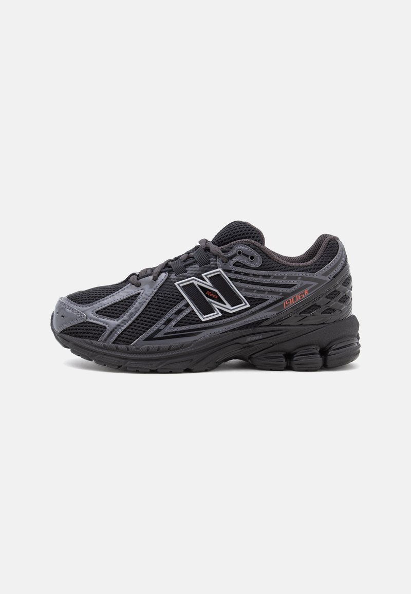 Μαύρο και γκρι αθλητικό παπούτσι New Balance 1906R με ύφασμα από δίχτυ, μαλακή σόλα και λευκό λογότυπο "N" στη πλευρά, φαίνεται από το εξωτερικό πλευρό.