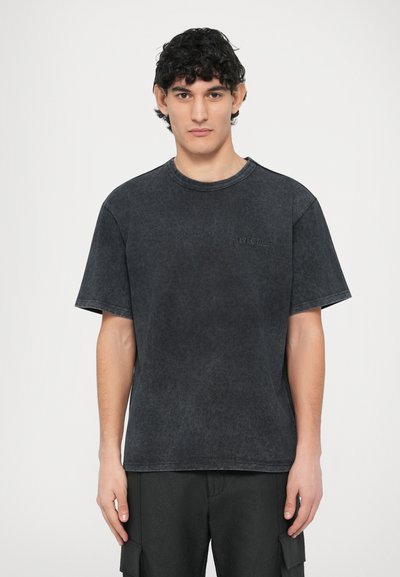 T-shirt en coton gris foncé à texture douce, manches courtes, col rond et petit logo embossé sur la poitrine gauche.