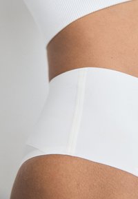 Hoge taille witte onderbroek met een gladde textuur, voorzien van een naaddetail aan de zijkant, ontworpen voor comfort en bedekking.