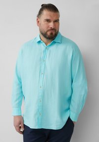 Lichtblauw linnen shirt met lange mouwen, een knoopsluiting aan de voorkant en een ontspannen pasvorm. Beschikt over een puntkraag en gouden knopen.