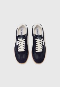 Navy sneakers med overdel av semsket skinn og syntetisk lær, hvite lisser, gummisåle og et klassisk sporty design. Inkluderer logo på tungen.