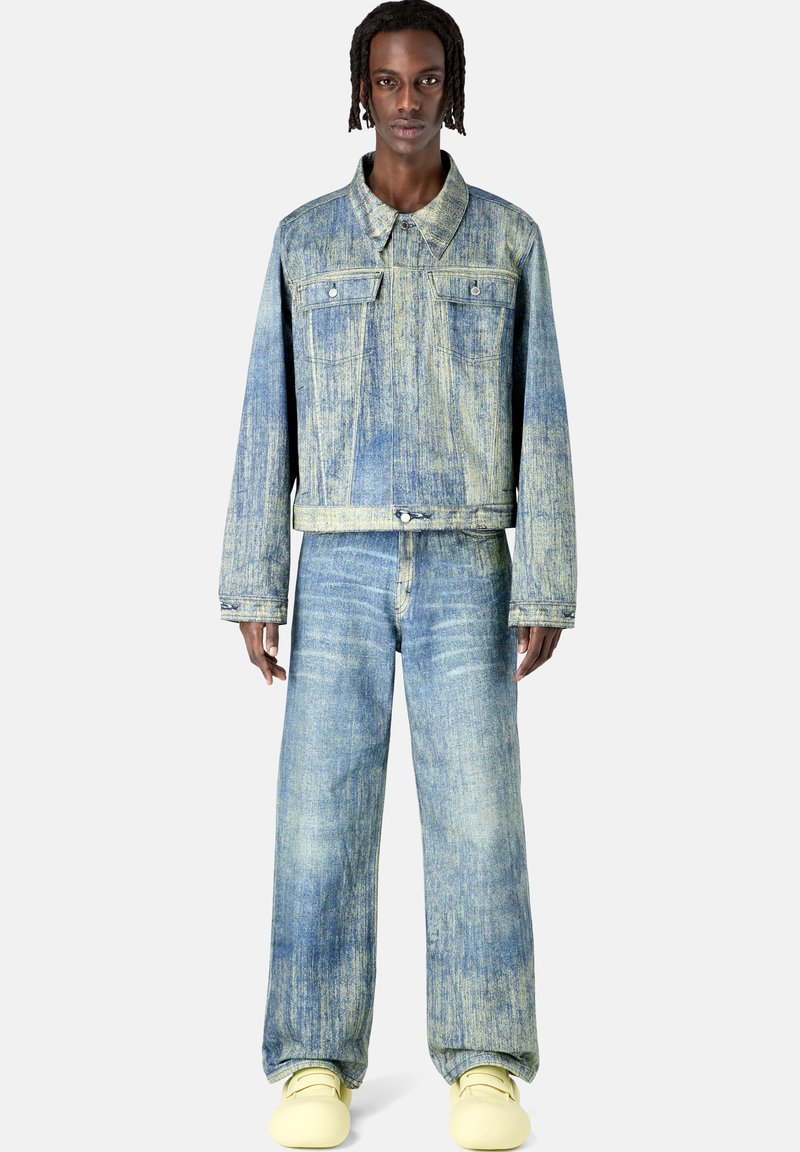 Chaqueta de mezclilla azul claro con un corte recto, dos bolsillos frontales y jeans de pierna ancha a juego. Presenta una textura descolorida y un ajuste holgado.