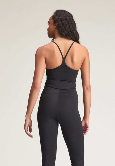 Black athletic tank top with adjustable thin straps, fitted design, and soft texture, paired with matching high-waisted leggings.