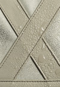 Il tessuto resistente all'acqua presenta un colore grigio chiaro con motivi a cucitura incrociata e gocce sulla superficie.
