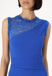 Vestido azul com decote de renda floral e ornamentos de renda intrincados, apresentado com um torso ajustado e textura de tecido suave.