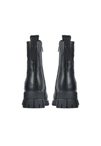 Botas de cuero negras hasta el tobillo con suelas gruesas, cremalleras laterales y un detalle de tela en el talón. Textura suave y diseño elegante.