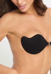 Black adhesive bra with a unique contour shape, featuring a smooth texture and a clasp for secure fit. Skin tone visible in background.