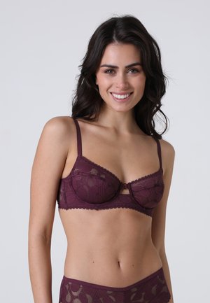 Reggiseno in pizzo bordeaux con stecche, motivo floreale, bordi ondulati e spalline regolabili. Presenta un piccolo dettaglio a fiocco centrale.