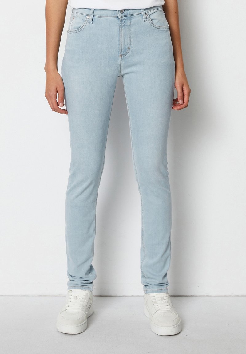 Vaqueros de mezclilla azul claro con un corte slim. Las características incluyen cinco bolsillos, una cremallera y costuras visibles a lo largo de las costuras.
