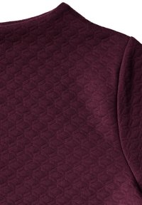 Burgundy-tyyppinen tekstiili, jossa on timanttikuosi. Tasainen pinta, jossa on pehmeä viimeistely ja pyöreä pääntie, joka esittelee suunnittelun yksityiskohtia.
