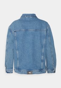 Veste en jean bleu clair, coupe décontractée, avec un col classique, une couture au dos et un patch logo à l'ourlet. Texture délavée.