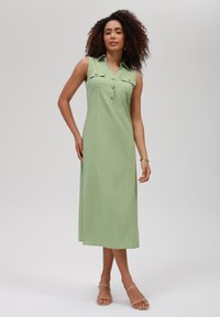 Abito maxi senza maniche di colore verde chiaro, con colletto, chiusura a bottoni sul davanti e due tasche sul petto; tessuto liscio, vestibilità rilassata.
