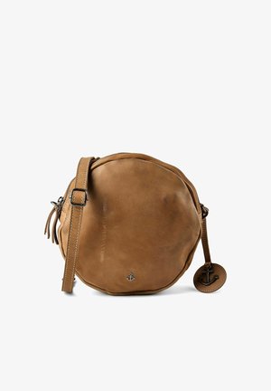 Bolso cruzado redondo de cuero marrón claro con correa ajustable, pequeño emblema metálico de ancla y charm de ancla a juego en una etiqueta de cuero.