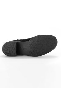 Semelle de chaussure noire avec un motif texturé, présentant un léger talon. La marque "Gabor" est embossée à la surface. Fini lisse dans l'ensemble.