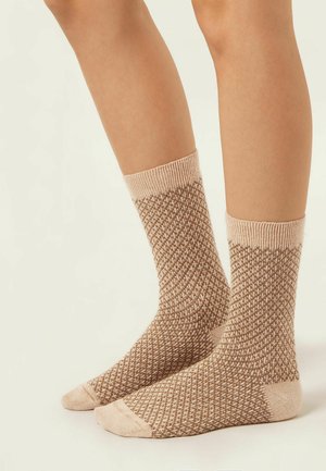 Chaussettes tricotées dans une palette de couleurs beige et marron, présentant un motif losange avec des bords côtelés et des zones de orteils et de talons renforcées.