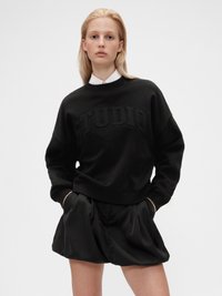 Sweatshirt noir avec texte en relief "STUDIO". Doté d'un col rond et de poignets côtelés, il est associé à un short plissé noir.