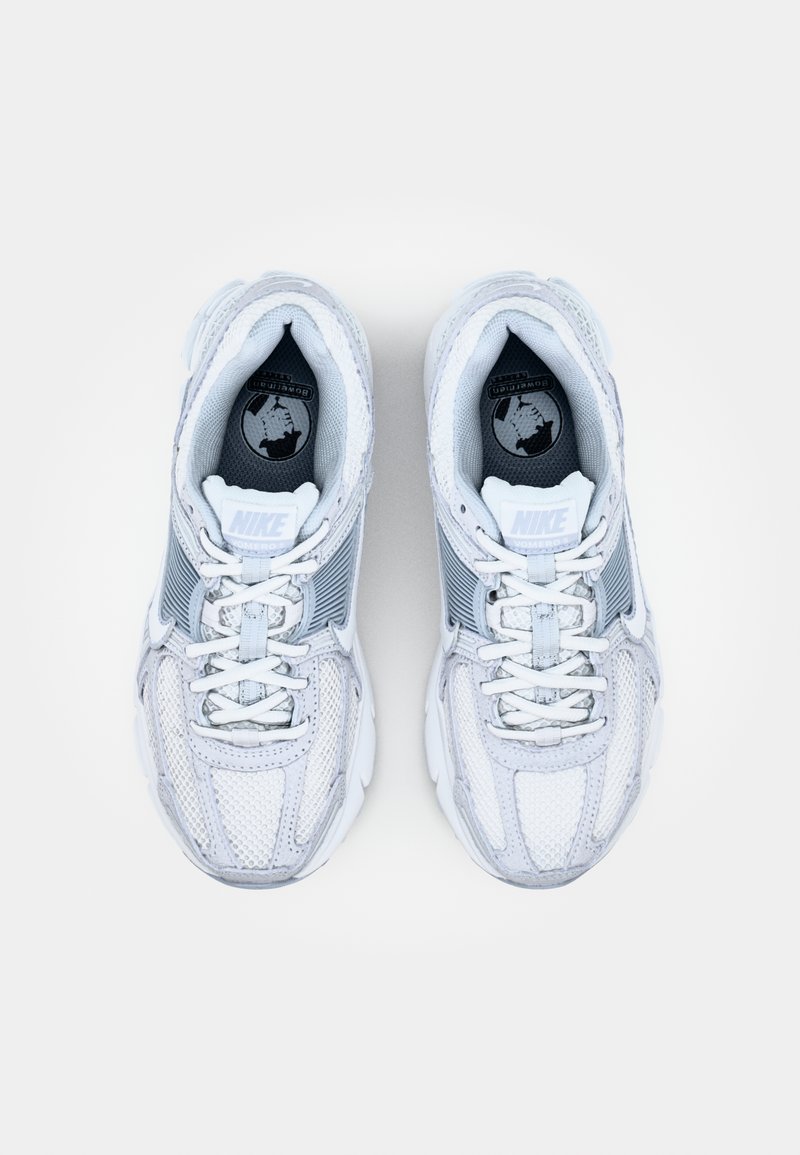 Sneakers Nike z dominującą białą siateczką u góry, szarymi akcentami, grubą białą podeszwą oraz niebieskim logo na języku.