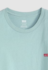Tricou din bumbac de culoare albastru deschis, cu guler rotund, mâneci scurte și un mic logo roșu Levi's pe pieptul stâng. Textură netedă, croială standard.