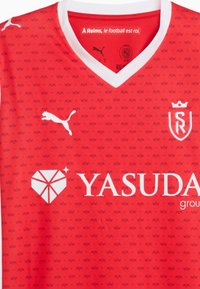Röd fotbollströja med vit Puma-logotyp, SR-klubbens emblem med krona, vit V-ringning, upprepande mönster av små kronor och Yasuda-sponsorlogotyp.