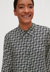 Long-sleeve shirt in black featuring a white geometric pattern. Collared with button closure, smooth fabric, and a tailored fit.