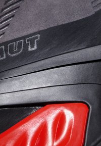 Czarne buty wspinaczkowe z teksturowanym szarym wierzchem, gumową podeszwą i jaskrawoczerwonymi akcentami. Posiadają logo oraz wyraźne wzory wzdłuż boków.