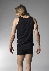 Black sleeveless tank top and black shorts worn by a person, showcasing a fitted design, smooth texture, and various tattoos on arms.